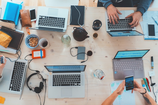 A desk full of our employees working on laptops, brainstorming ideas, and collaborating on projects.